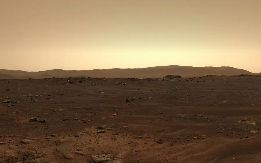 NASA's photo of the crater floor: rust-coloured ground, scattered rocks and low hills on the horizon